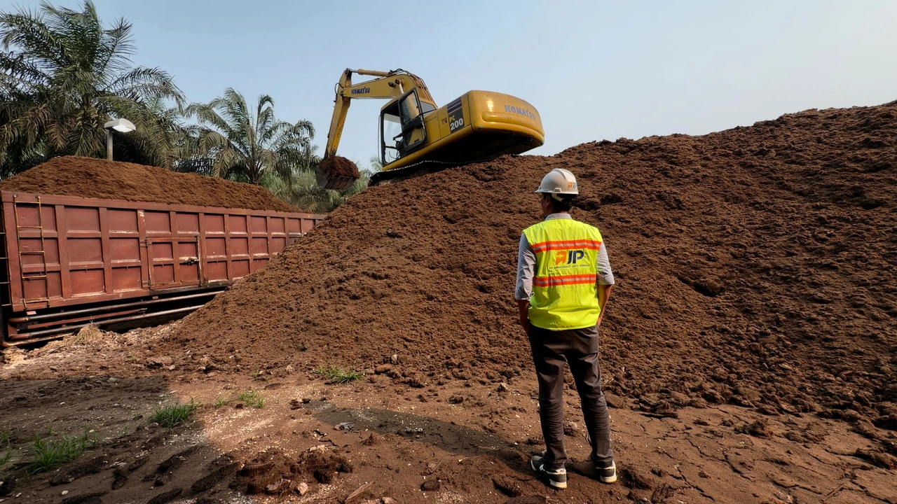 AJP representative observing palm mesocarp fibre loading beside a stockpile and truck.